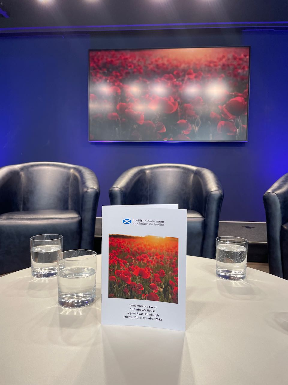 The booklet for the 2022 Remembrance Day ceremony at St Andrews House, on a table, with glasses of water